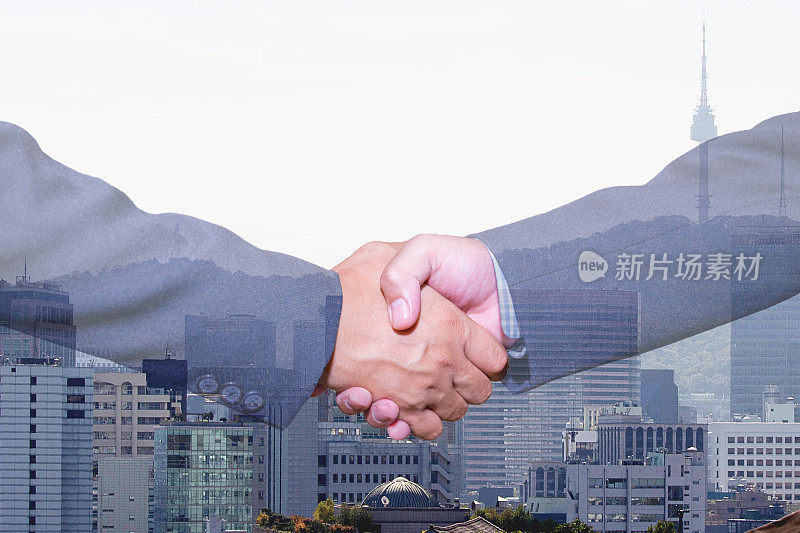 握手和城市双重曝光。握手和商务人士的概念。两名男子握手孤立的城市景观背景。