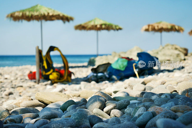 三把阳伞在地中海孤独的卵石海滩上