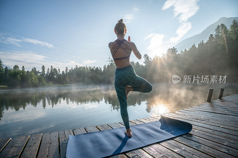 女人练习瑜伽姿势在自然，湖码头