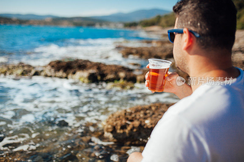 在海滩上喝啤酒的男人