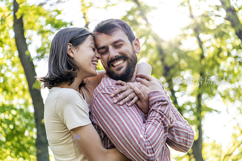 一对年轻夫妇正在公园里享受春天。他们在一起的时候，爱得更深。年轻的情侣在公园里微笑着拥抱。