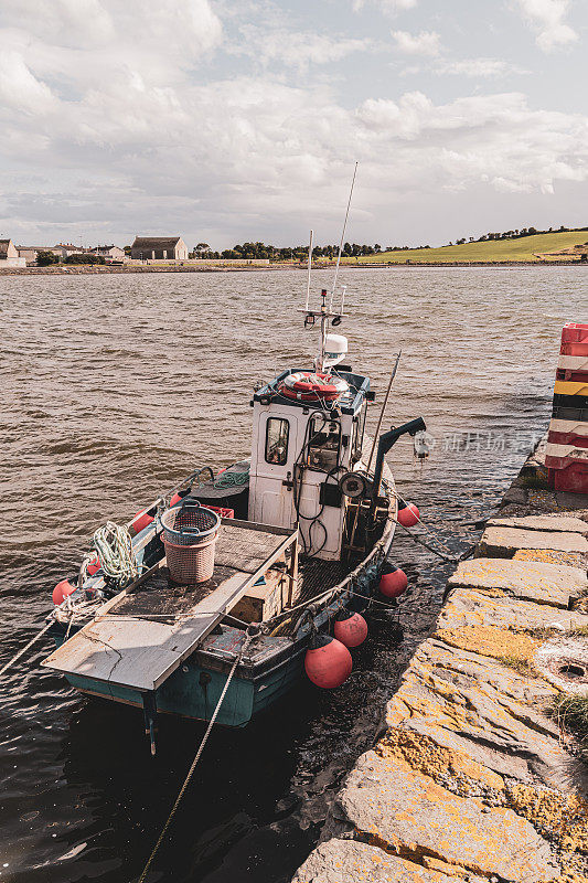 一艘近海渔船停泊在一个石头码头上
