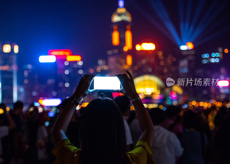 女人和著名的香港城市景观地标景观，使用手机