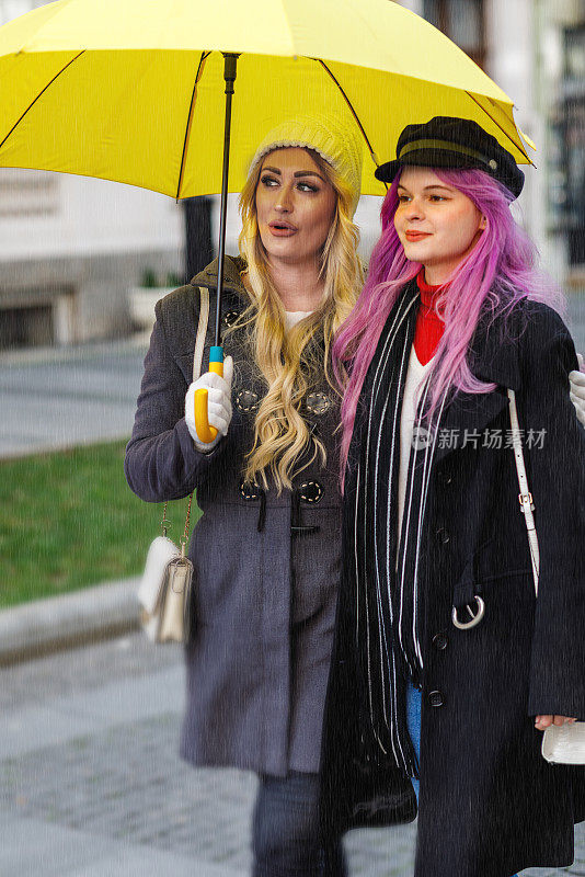 两个迷人的年轻女子在一个雨天走在城市的街道上。