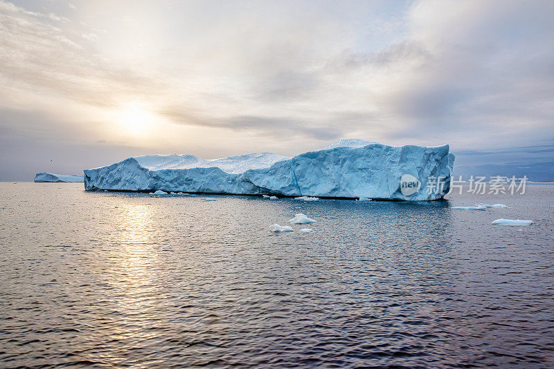 日落时的冰山。太阳倒映在海面上。迪斯科湾。西格陵兰岛。夏天的午夜太阳和冰山。冰峡湾的大蓝冰。受气候变化和全球变暖影响