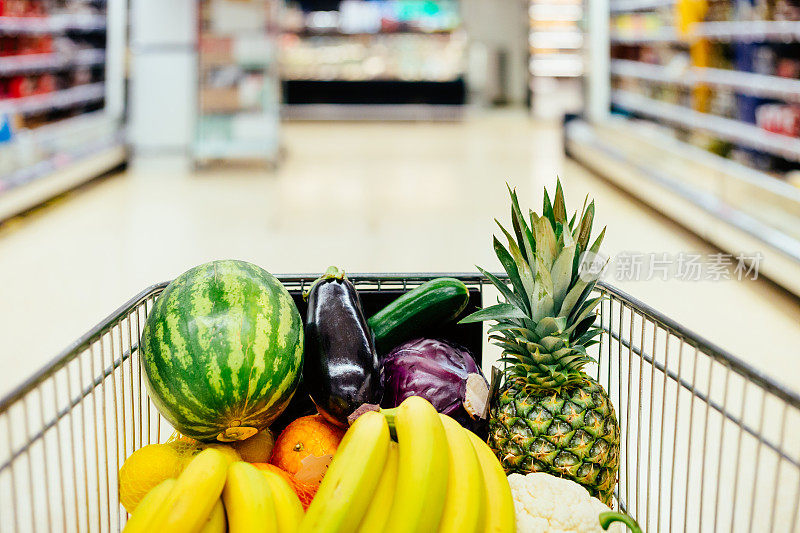 超市里装满健康水果和蔬菜的购物车