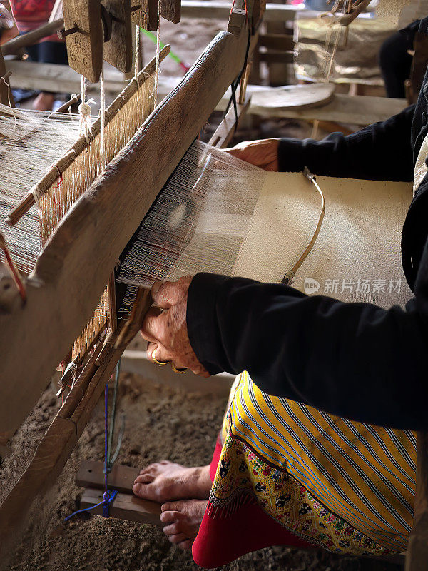 近距离观看当地老年妇女用木制织机手工编织，泰国传统文化生活方式，丝绸和棉花纺织品，艺术家工匠手工制作的手工艺品
