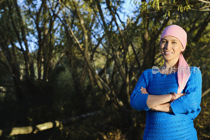 在自然森林里，一位与癌症抗争的妇女看着镜头微笑。