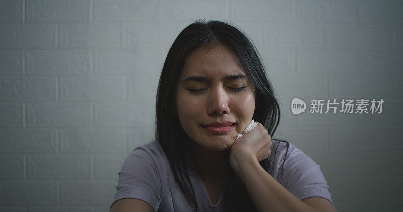 悲伤沮丧的年轻亚洲女子独自坐在家里的地板上哭泣