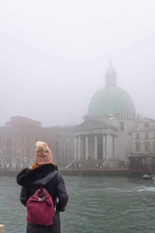 意大利威尼斯，身穿保暖衣服的女子站在大运河码头的后视图