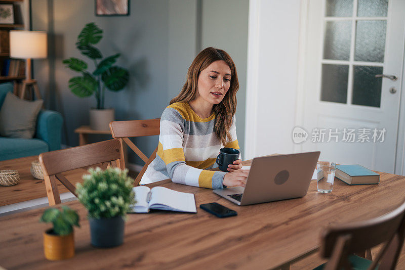 一个成熟的女人在家工作，使用笔记本电脑。