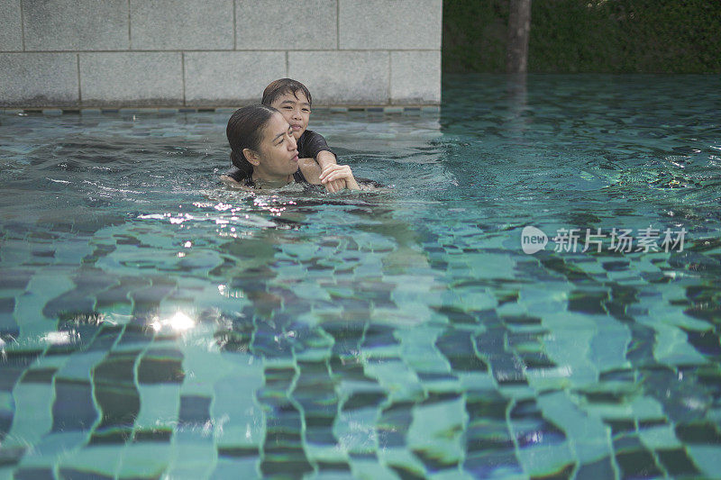 妈妈和男孩在游泳池里游泳