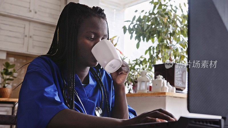 黑人女性卫生工作者在家里用笔记本电脑穿着工作服的生活方式。