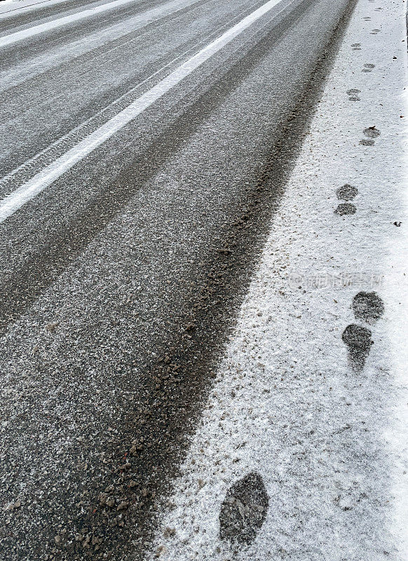 街道上新下的软雪上留下了汽车轮胎的印记。