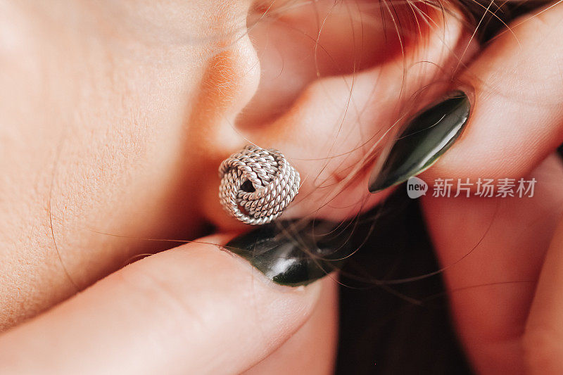 银色耳环背景。特写女人的耳朵。戴耳环。银球螺柱。闪亮的珠宝。珍贵的情人节礼物。