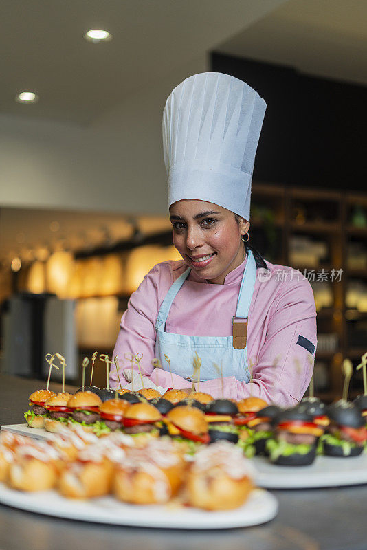 拉丁女职业厨师站在一家漂亮餐厅的厨房里准备美味的菜肴