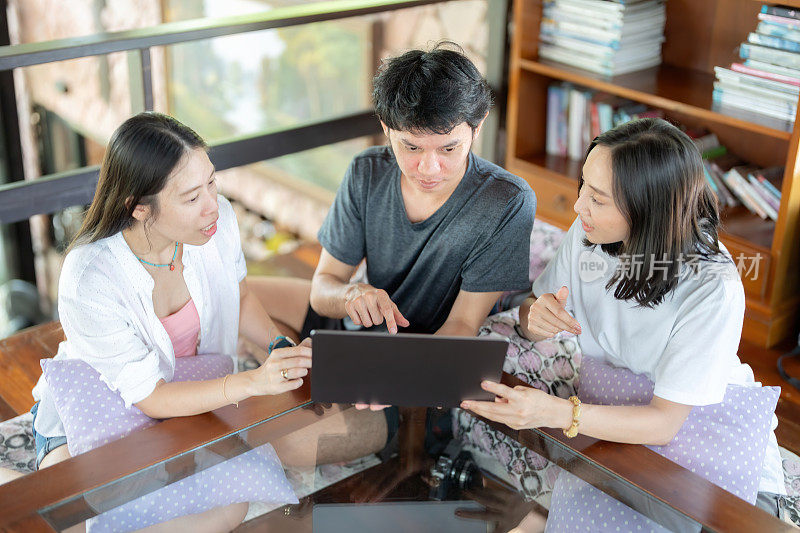 俯视图3名亚洲男女学生穿着休闲服做毕业设计。在大学的教员图书馆里，桌子上有一台笔记本电脑，你可以用来聊天。