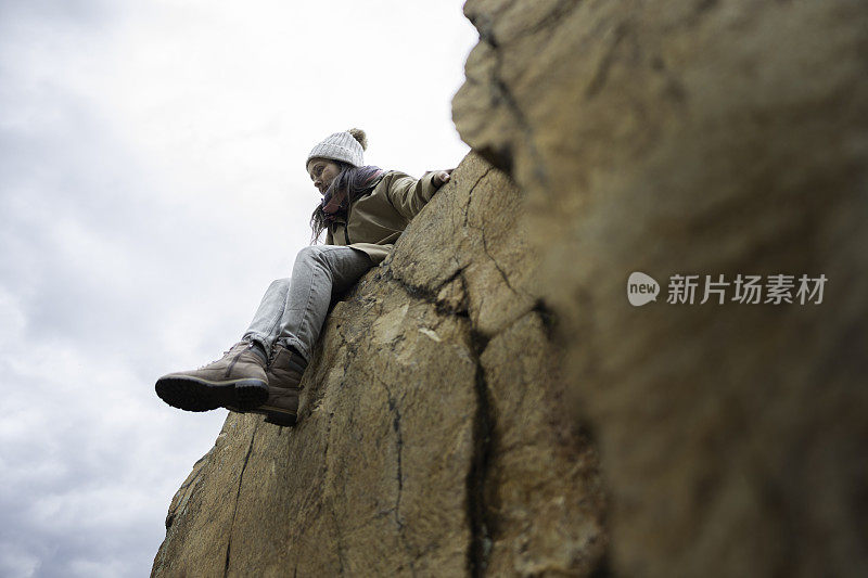 女人坐在悬崖上。回归自然的独自旅行。