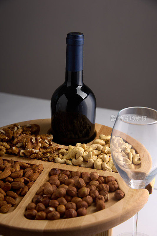 一瓶酒和一个空杯子，杯子放在用坚果做成的木头架子上