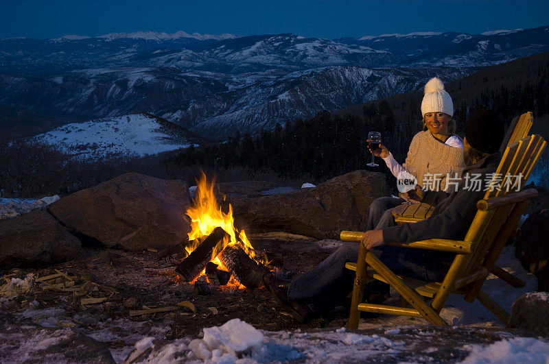 一对夫妇坐在壁炉边，在科罗拉多州的冬季山脉