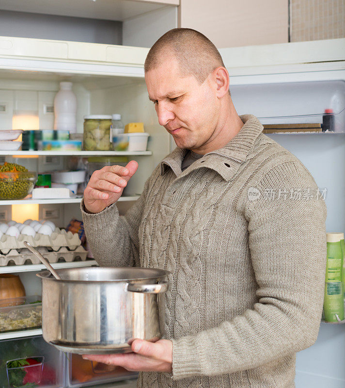 一个男人拿着不干净的食物靠近冰箱