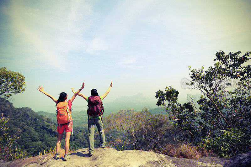 两个成功徒步旅行的朋友在山顶欣赏风景