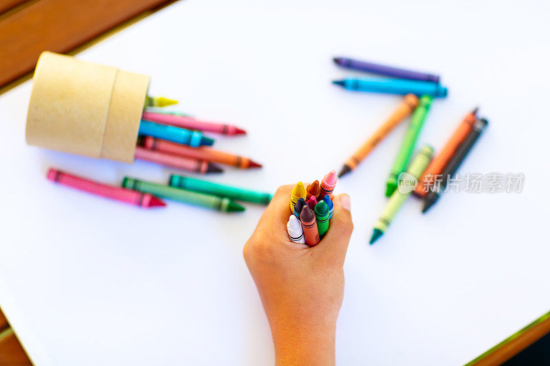 孩子的手上有很多彩色蜡笔