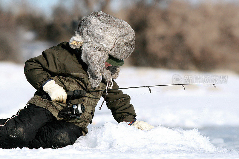 穿着全套冬装的人们在结冰的湖面上钓鱼