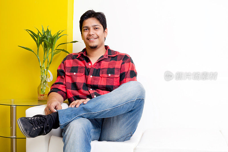 一个年轻的印度男子坐在沙发上
