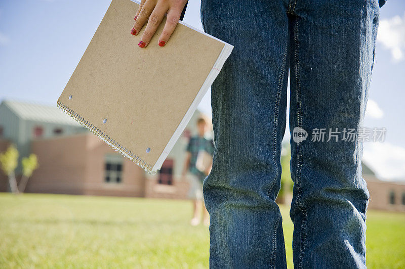 年轻的女学生在学校等待带着笔记本的朋友