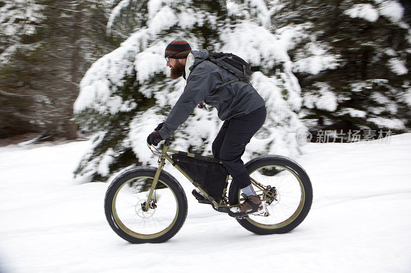 在雪地里骑着胖自行车的大胡子男人