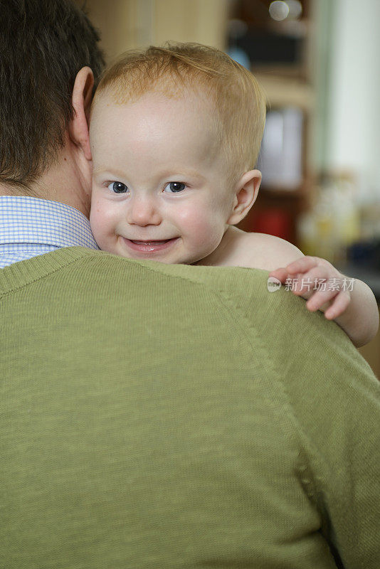 Smiley蹒跚学步的孩子，安全地坐在爸爸的肩膀上