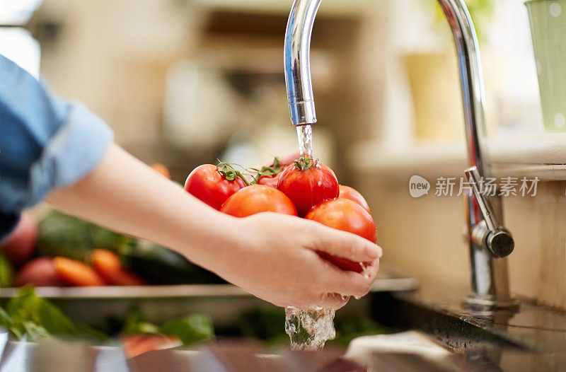 女人在水槽下洗西红柿的特写图像