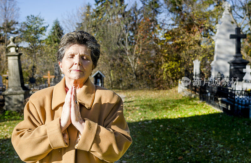 罗马尼亚，一名妇女在墓地祈祷，缅怀死者
