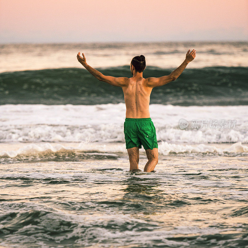 日落时分，一个年轻人在长岛的海里游泳