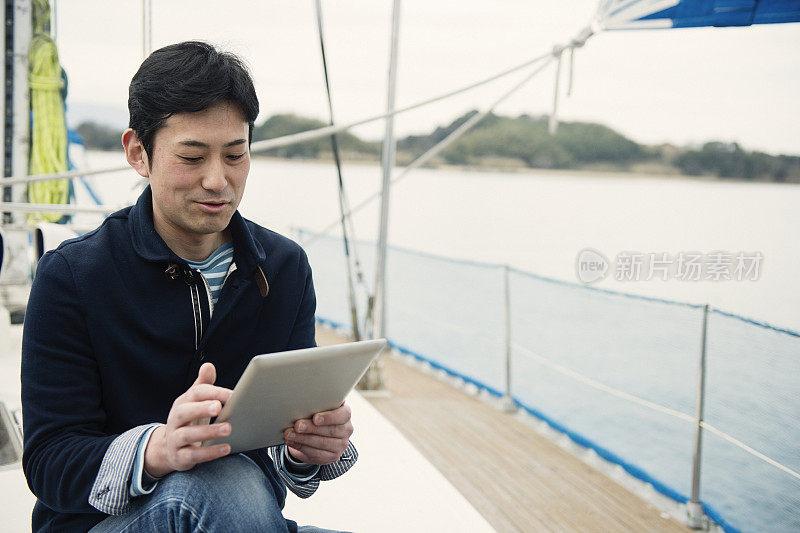 一个在游艇上用平板电脑的成年人