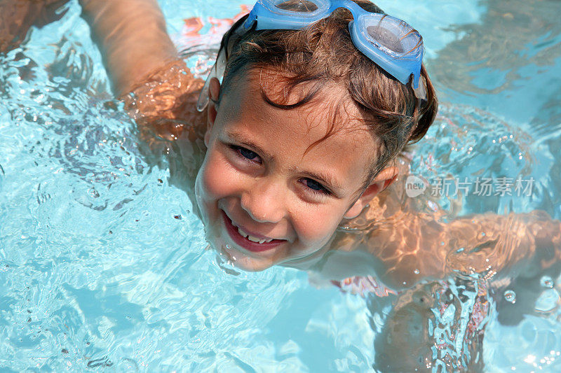 暑假男孩在游泳池里微笑着游泳