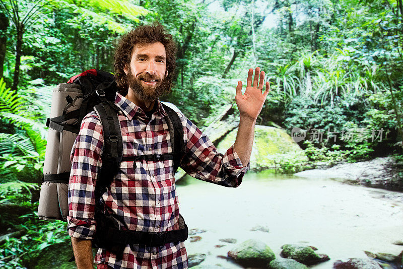 微笑的男性徒步旅行者在雨林和挥手
