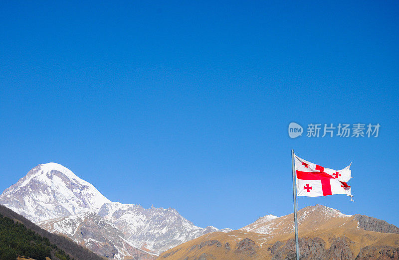 高加索山脉在春天有雪和格鲁吉亚国旗
