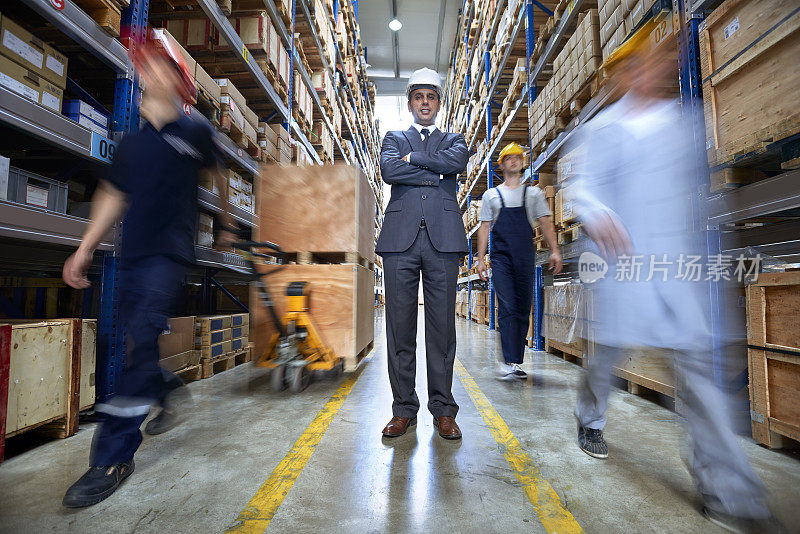 经理和工人们走在仓库的过道上