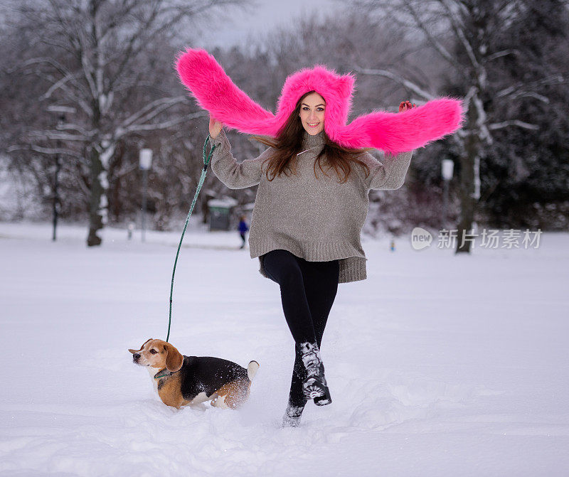 快乐的女人和最好的朋友比格犬在雪中玩耍