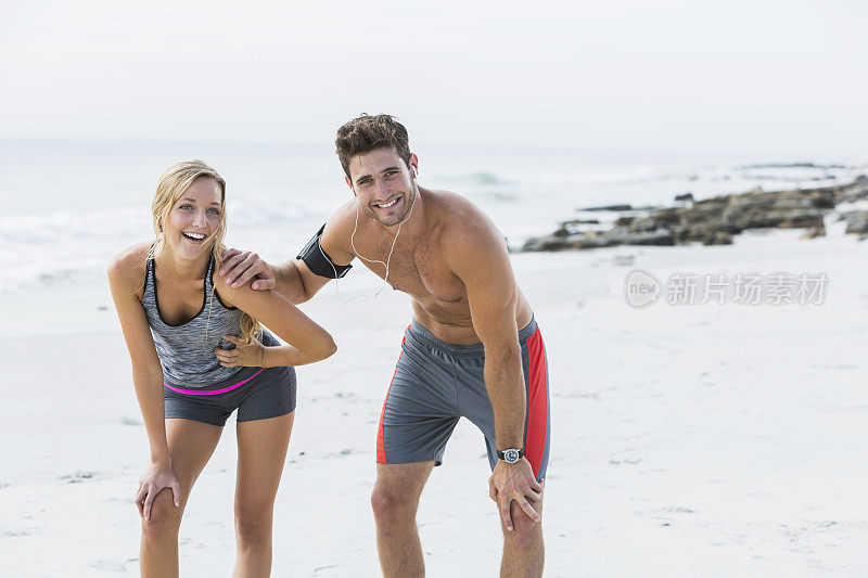 一对年轻夫妇在海滩上跑步后休息