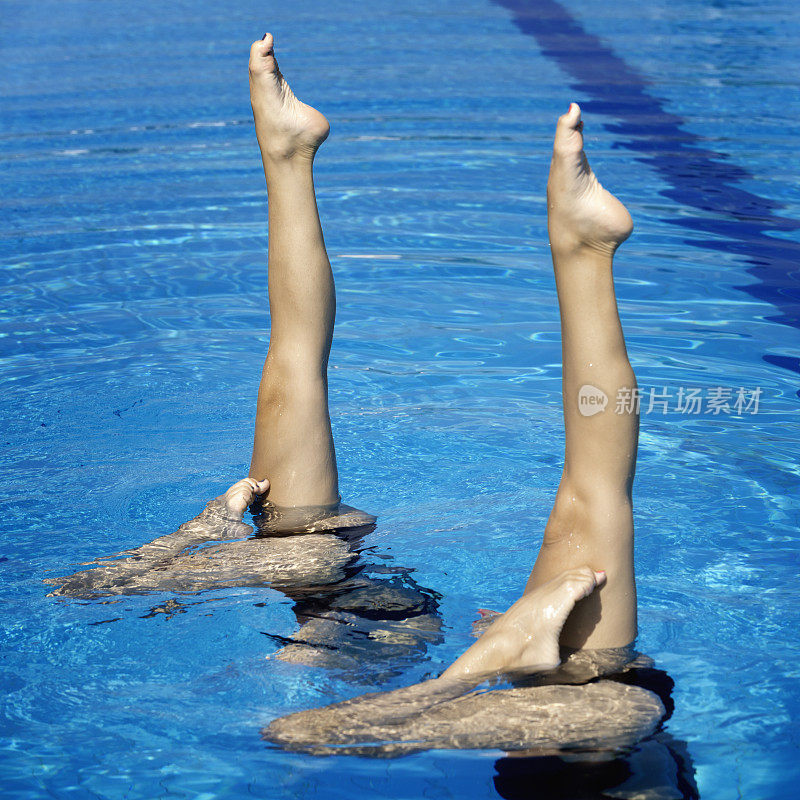 两名女子花样游泳运动员，脚朝上