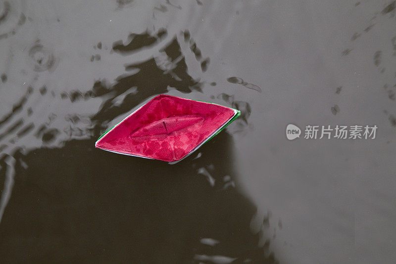 蓝色的纸船在雨中漂浮在水面上