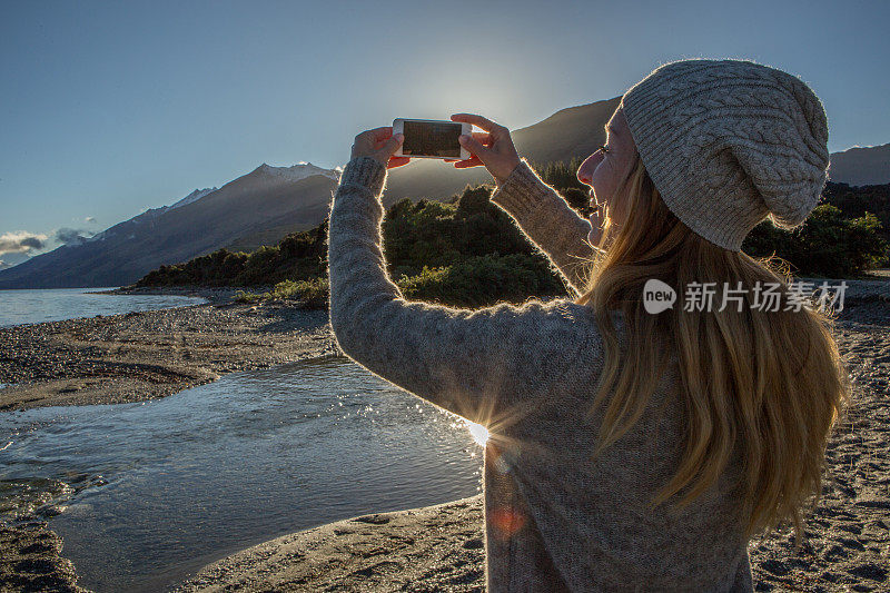 年轻女子用智能手机拍摄山景