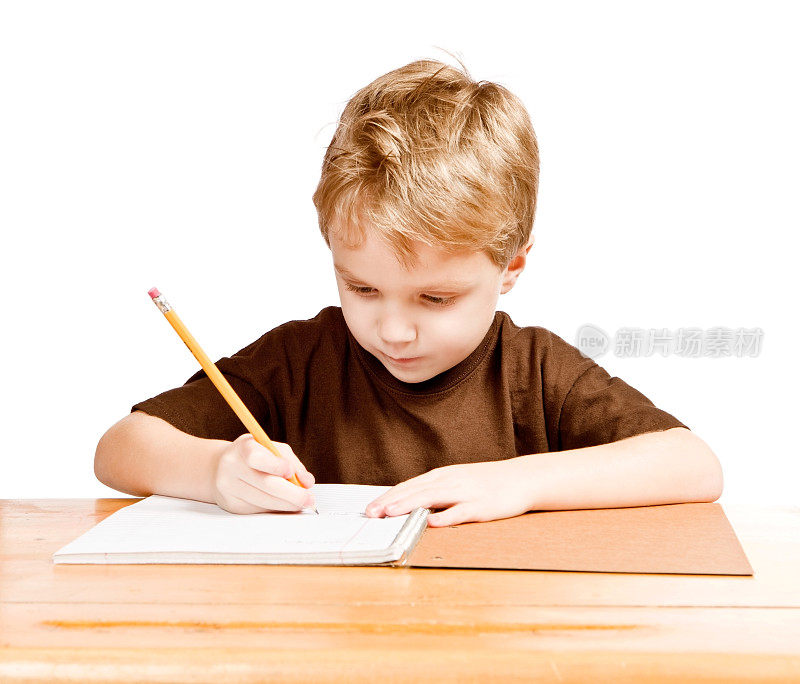 用铅笔在书桌上写笔记本的男孩