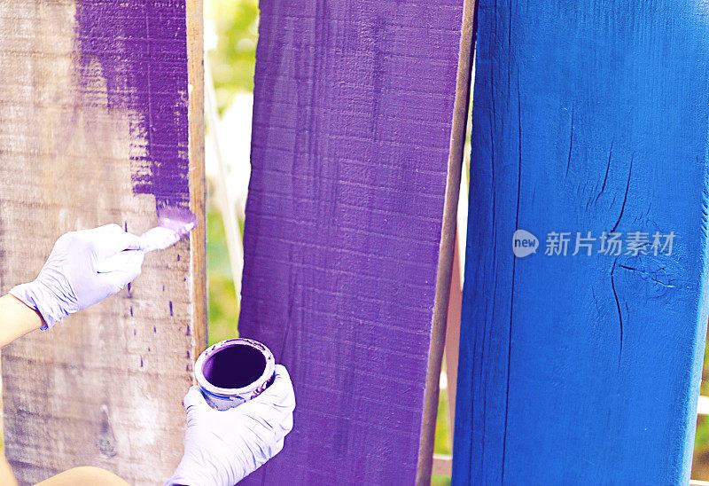 女人用画笔把木板涂成紫色和蓝色