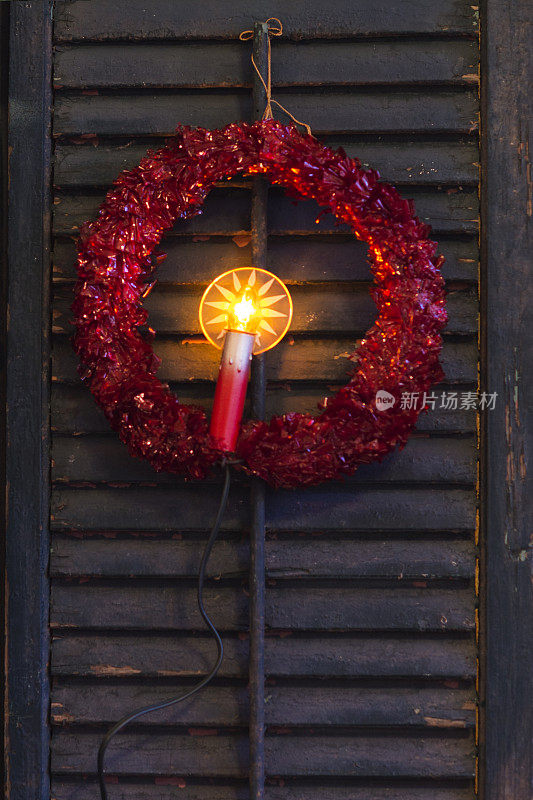 棕色百叶窗上的红色花环，上面插着蜡烛