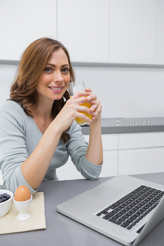 吃早餐时用笔记本电脑的漂亮女人，面带微笑
