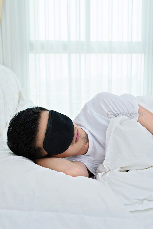 在床上戴着睡眠面罩的年轻人